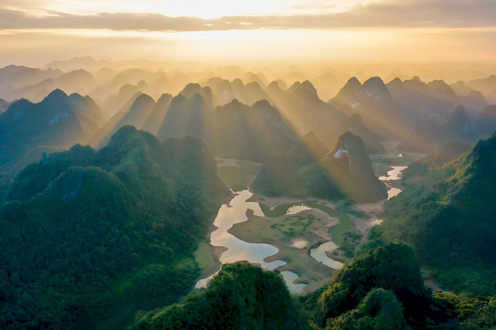 Panoramic views of Thang Hen Lake’s crystal-clear waters framed by towering limestone cliffs and lush green forests